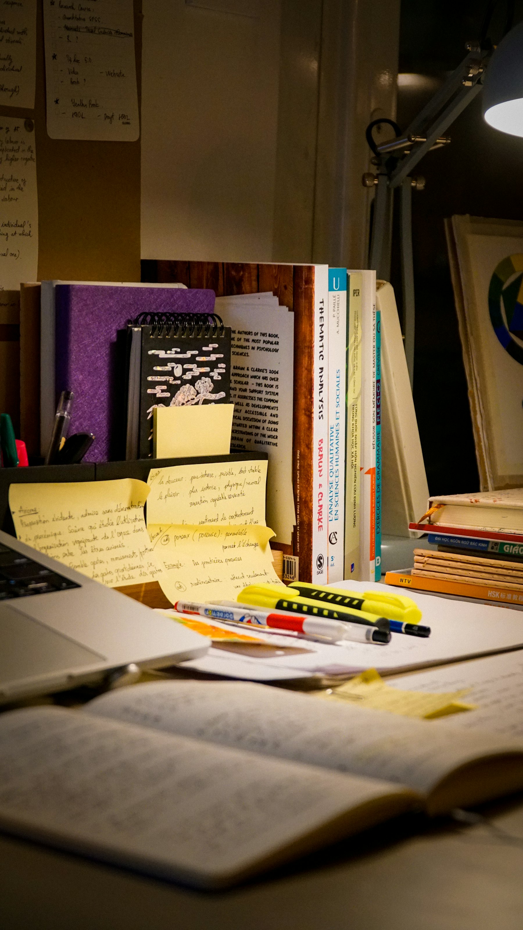 Reference books and handwritten notes spread across a research desk.