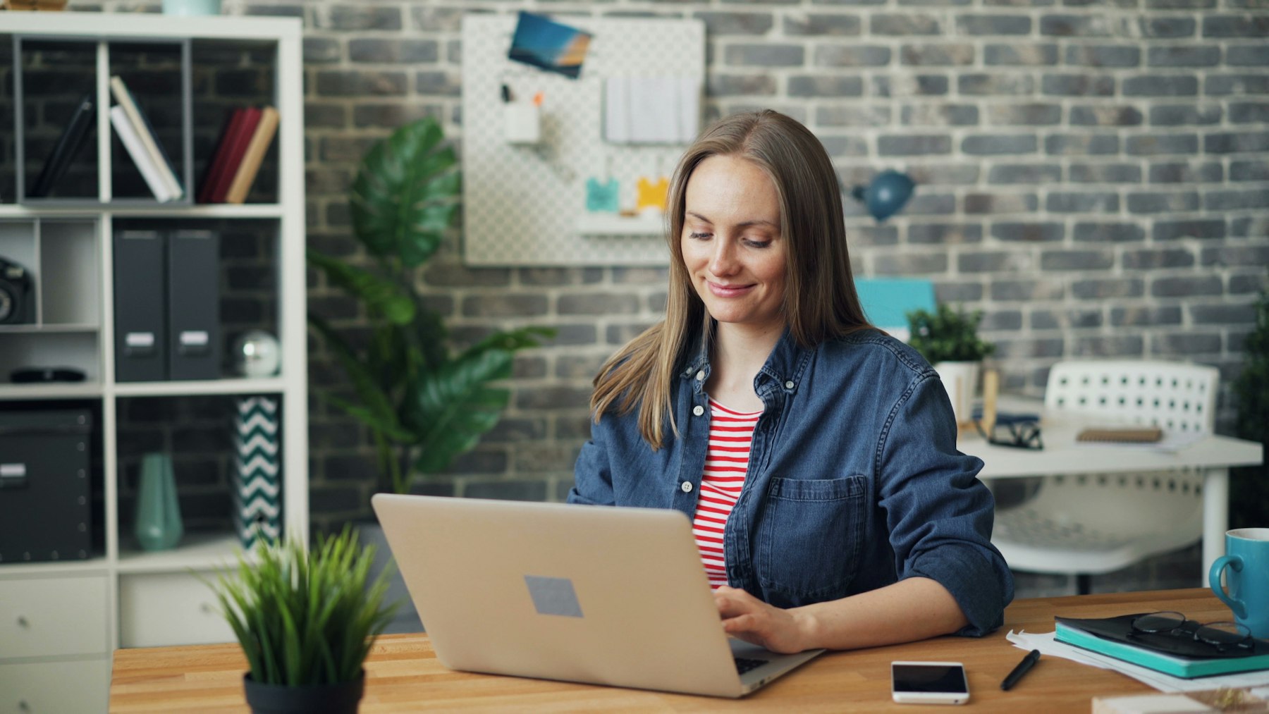 An employee smiling while checking her payslip and leave balance on a laptop.
