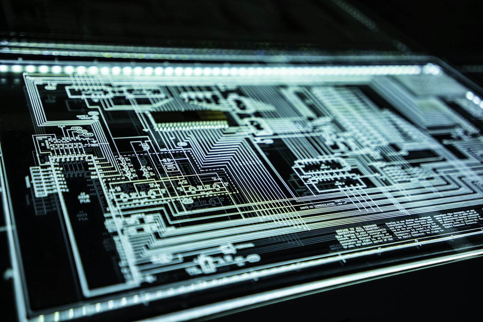 An illuminated circuit board schematic on a backlit panel, resembling an architectural blueprint.