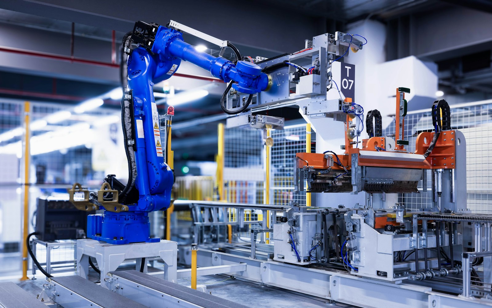 A blue industrial robotic arm performing an automated task on a factory assembly line.