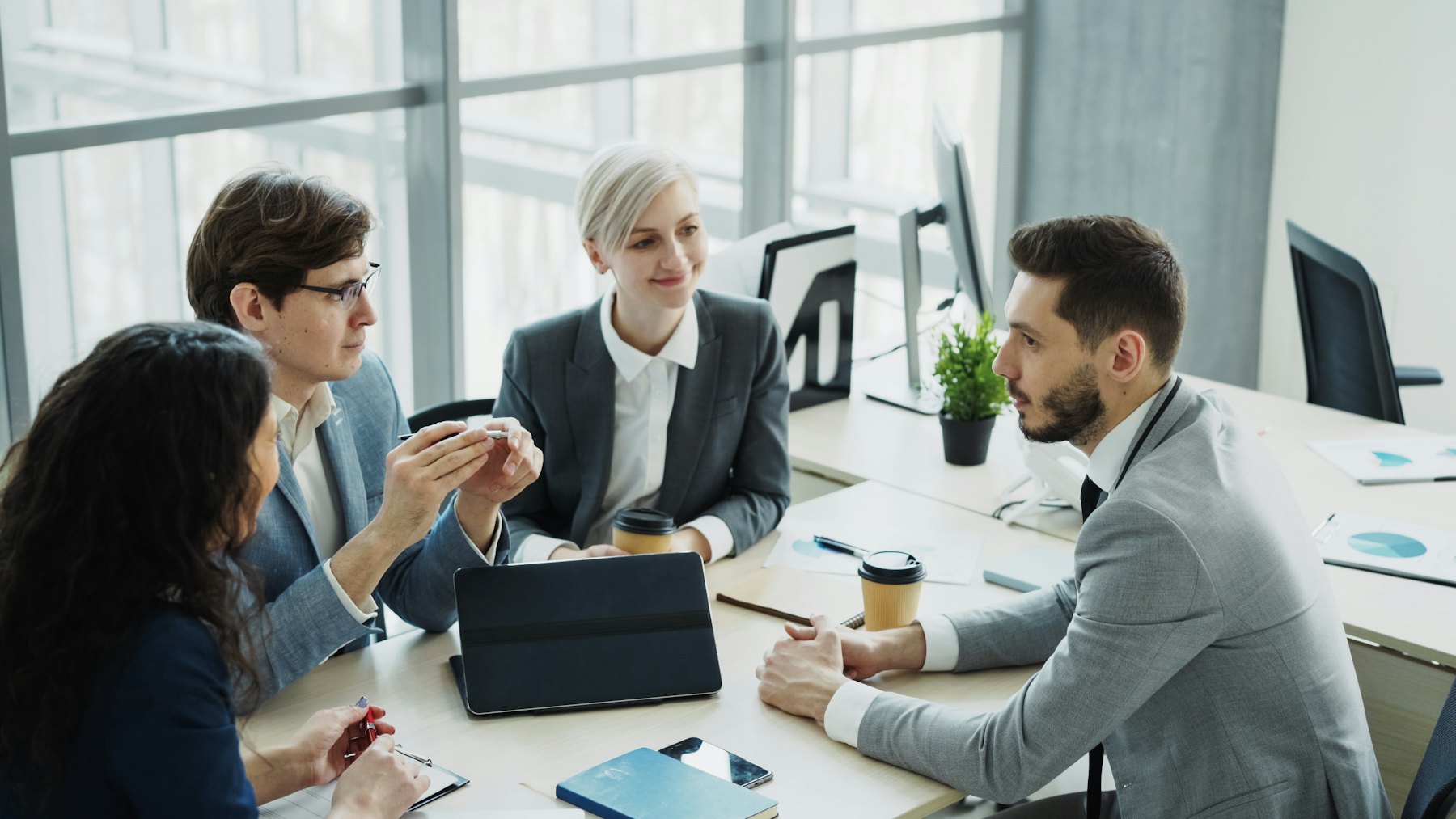 A small group discussing a decision around a table in a bright office.